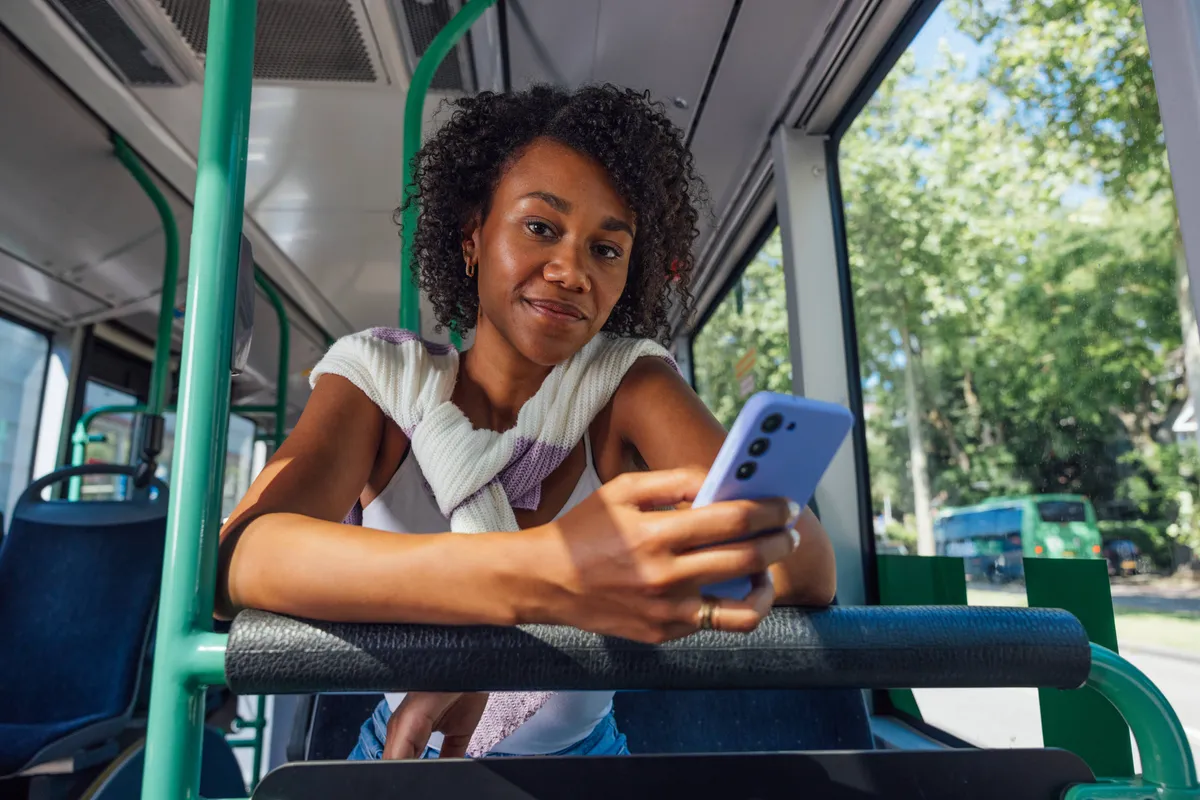 vrouw in bus met mobiel in hand