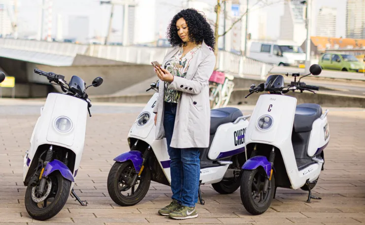 Vrouw staat bij 3 deelscooters